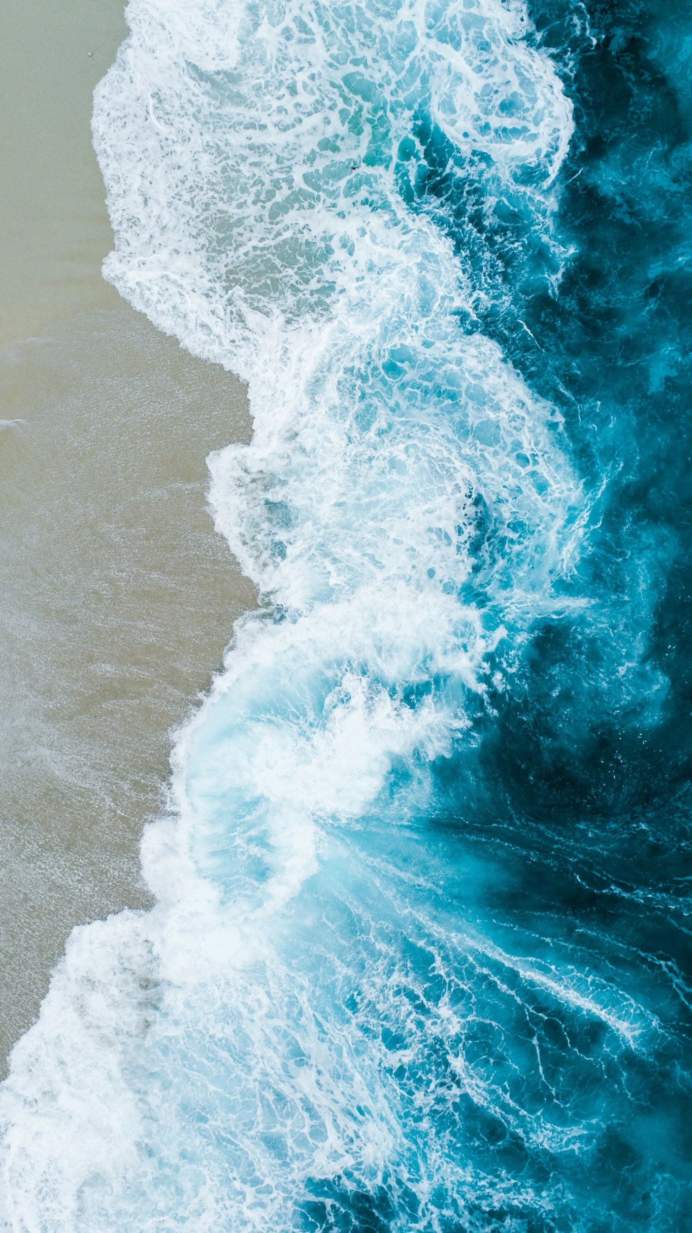 Aerial view of ocean waves washing onto a sandy shore