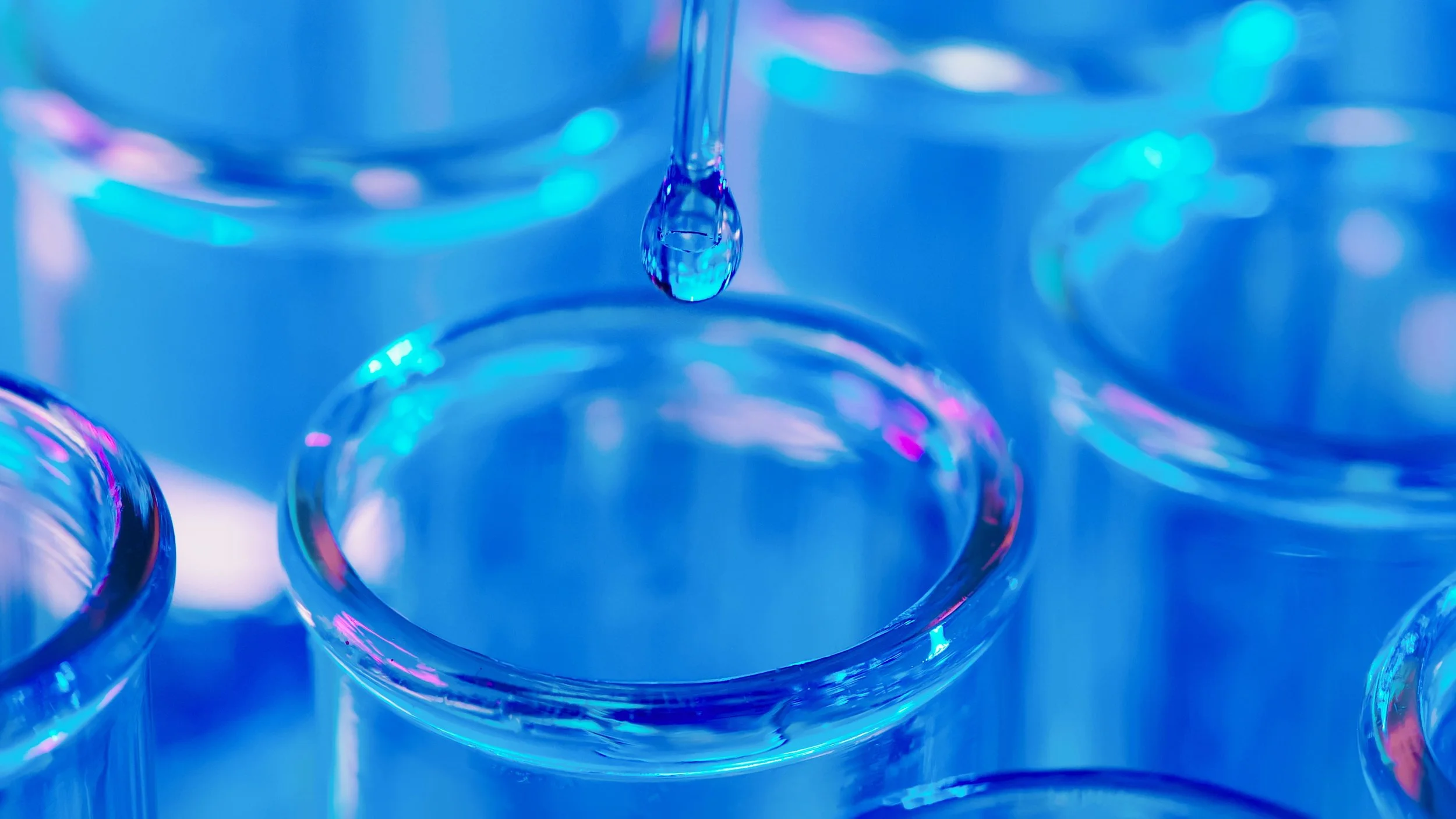 A laboratory pipette releasing a droplet into glass vials